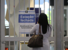 Passageira parada em frente ao portão de uma estação do Metrô de São Paulo