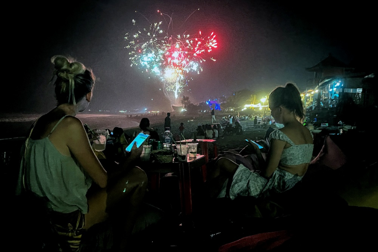 Fogos de artifício iluminam o céu noturno enquanto os foliões celebram a véspera de Ano Novo na praia em 31 de dezembro de 2023, no distrito de Kerobokan, na ilha turística de Bali