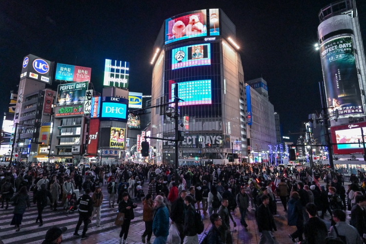 As pessoas atravessam o cruzamento de Shibuya algumas horas antes da meia-noite da véspera de Ano Novo no centro de Tóquio