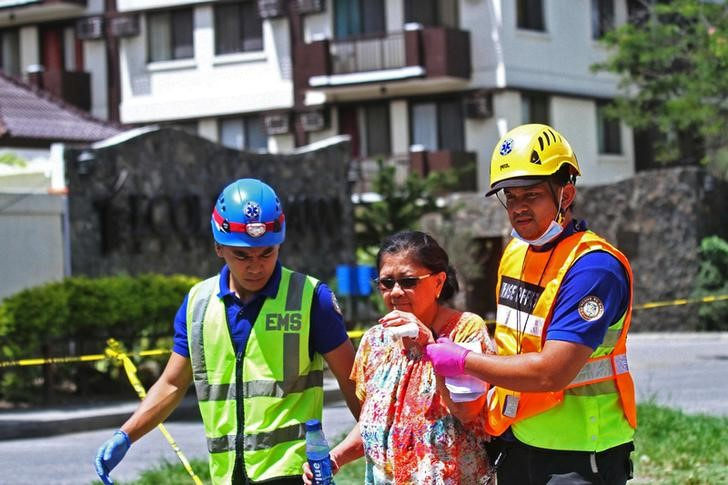 Imagen de archivo de operarios de emergencias ayudando a la evacuación de una residente de un condominio tras un sismo de magnitud 6,5 en Davao City, Mindanao, Filipinas.