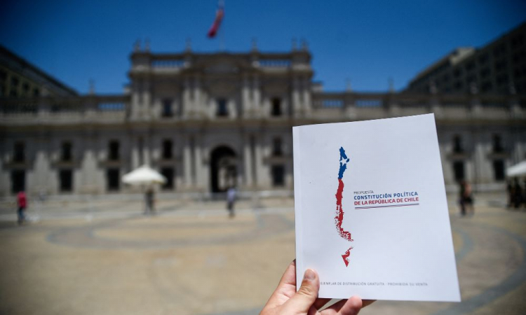 Homem segura cópia da proposta da Nova constituição do Chile em frente ao Palácio Presidencial La Moneda