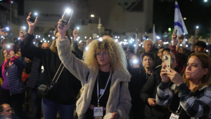 Familiares e apoiadores de reféns israelenses detidos pelo Hamas em Gaza, levantam as luzes de seus telefones pedindo sua libertação durante um protesto em frente à base militar de Kirya em Tel Aviv