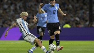 O meio-campista argentino Rodrigo De Paul (esq.) e o zagueiro uruguaio Matias Vina (dir.) brigam pela bola durante a partida de futebol das eliminatórias sul-americanas para a Copa
