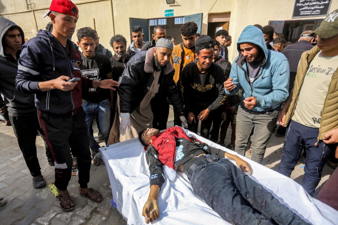 Pessoas se reúnem em torno do corpo de um jovem que foi morto no bombardeio israelense