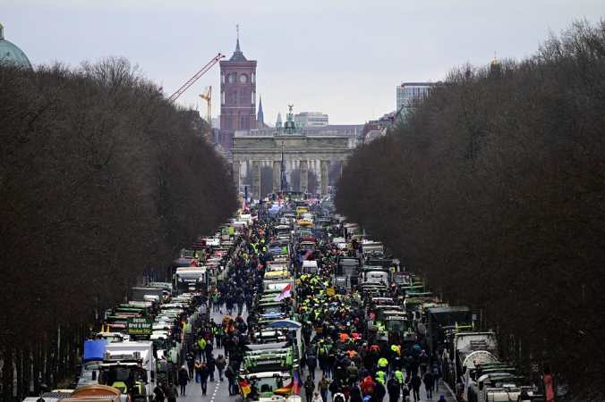 Tratores e caminhões estão em frente ao marco de Berlim, o Portão de Brandemburgo, enquanto ao fundo pode ser vista a Prefeitura Vermelha da capital alemã durante um protesto de agricultores e motoristas de caminhão
