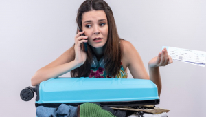 Mulher jovem viajante ansiosa falando ao telefone segurando passagens na parede branca isolada