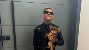 MC Cabelinho com um cachorrinho nos braços,. em frente a uma porta de apartamento