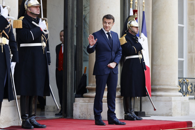 O presidente francês Emmanuel Macron acena antes da chegada do Emir do Catar, Sheikh Tamim bin Hamad al-Thani (invisível)