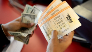Bilhetes da loteria em uma mão e dinheiro na outra