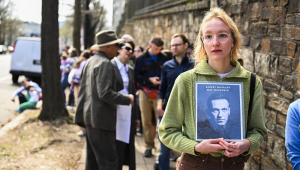 Mulher segura cartaz com o rosto de Navalny e a mensagem de que ele fo assassinado em fila para a votação na eleição russa em Washington