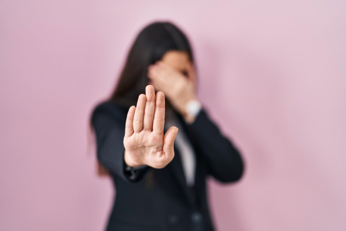 Mulher com a mão no rosto e a oura estendida