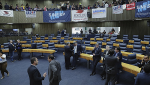 Plenário da Câmara dos Vereadores com sindcalistas com faixas ao fundo