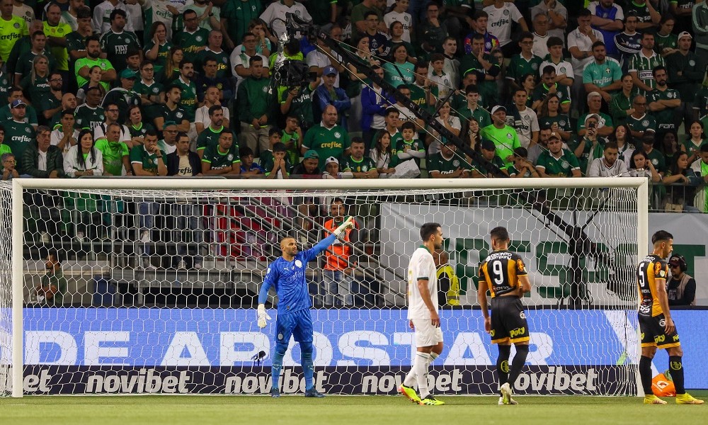 Weverton no gol do Palmeiras com outros jogadores na área e a torcida ao fundo