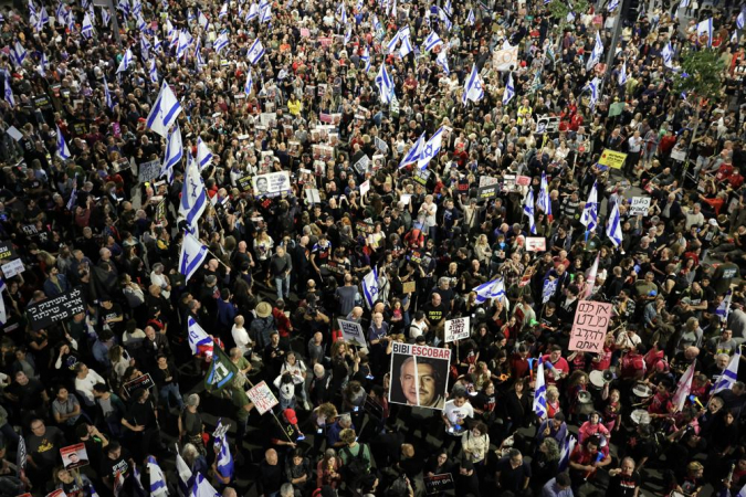 Familiares e apoiadores de reféns israelenses, detidos pelo Hamas em Gaza, seguram cartazes e bandeiras israelenses durante uma manifestação de protesto em frente ao quartel-general militar de Kirya, em Tel Aviv