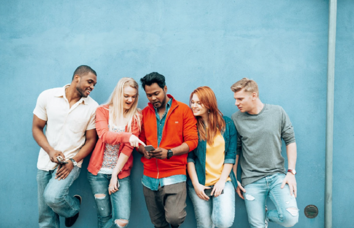 Cinco jovens com um no centro segurando o celular, e todos olhando