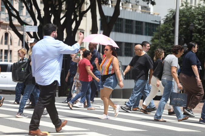 Pedestre se protege do sol no Viaduto do Chá, região central de São Paulo