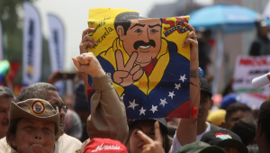 Uma pessoa levanta uma placa com o desenho do presidente venezuelano, Nicolás Maduro, durante uma concentração de apoiadores