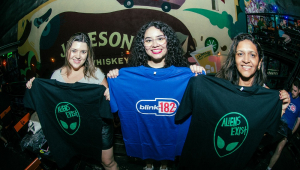 Fãs posam com as camisetas distribuídas no Baron Rock Bar, na Rua Augusta; Taynara (ao centro) não vai ao show