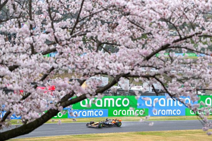 O piloto australiano da McLaren, Oscar Piastri, dirige enquanto é visto passando por cerejeiras em flor durante a segunda sessão de treinos