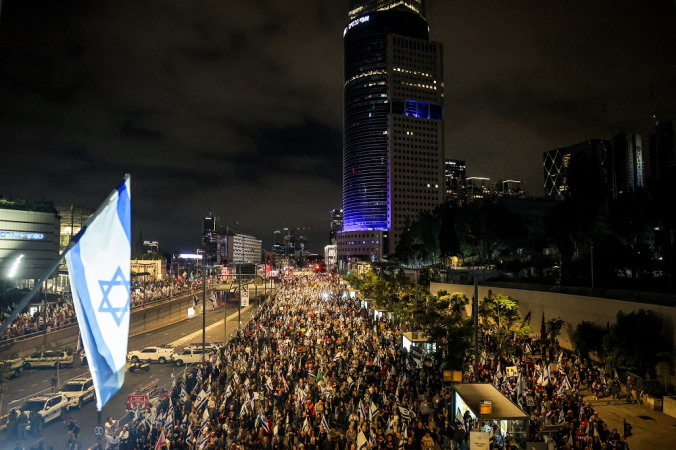 A polícia israelense bloqueia uma estrada enquanto manifestantes se reúnem durante uma manifestação antigovernamental perto da sede do Ministério da Defesa em Tel Aviv