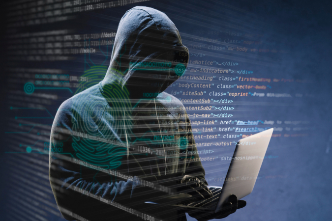 Hacker de capuz com notebook na mão e diversos códigos sobrepndo a imagem