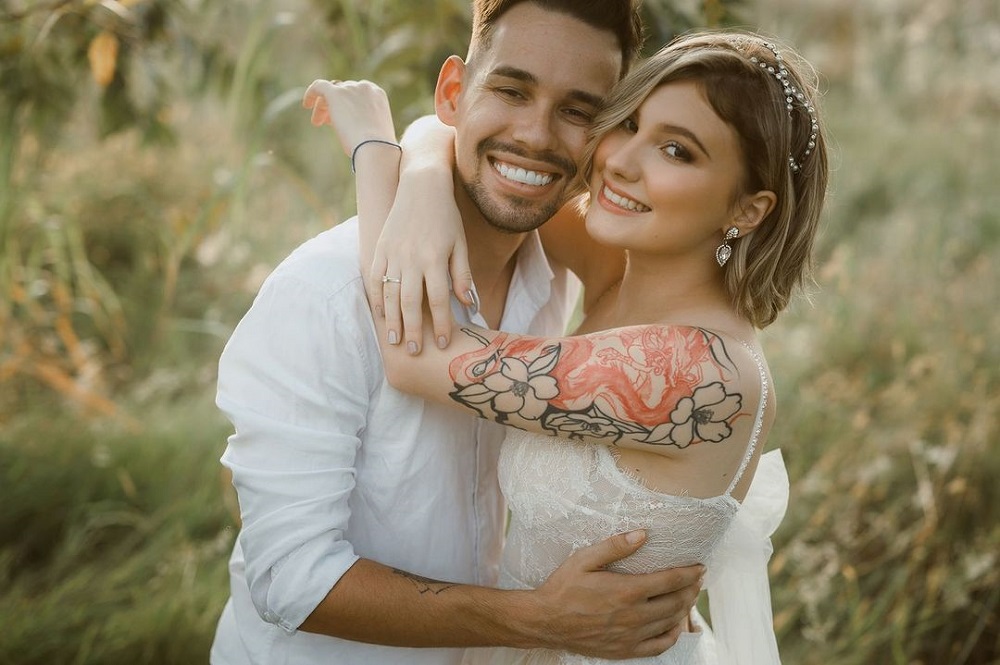 Isabela Veloso vestida de noiva e abraçada a seu noivo