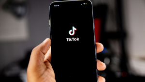 Mão segurando celular com símbolo do TikTok