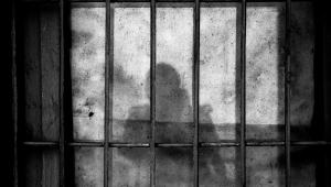 Sombra de uma pessoa atrás das grades em uma cela de prisão