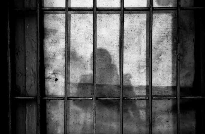 Sombra de uma pessoa atrás das grades em uma cela de prisão