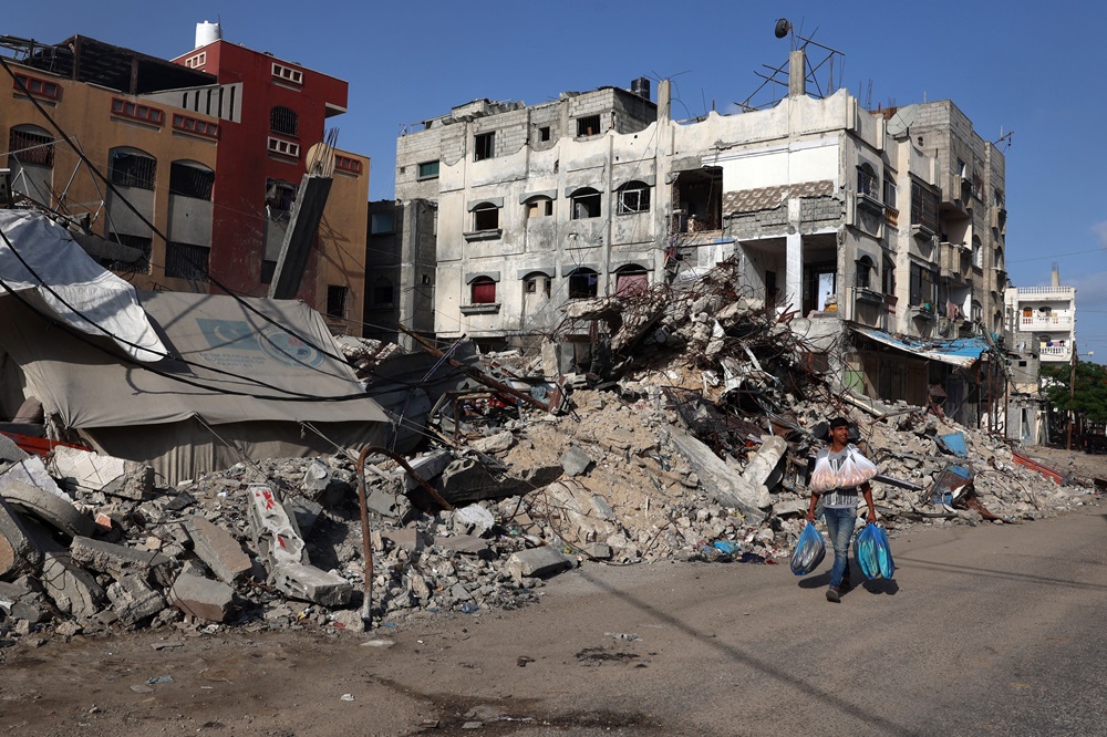Um homem palestino passa por um prédio destruído em Rafah, no sul da Faixa de Gaza, em 26 de maio
