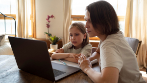 Mulher monitora criança com laptop