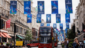 Pessoas andam de ônibus enquanto ele passa sob as decorações da final da UEFA Champions League na Regent Street em Londres