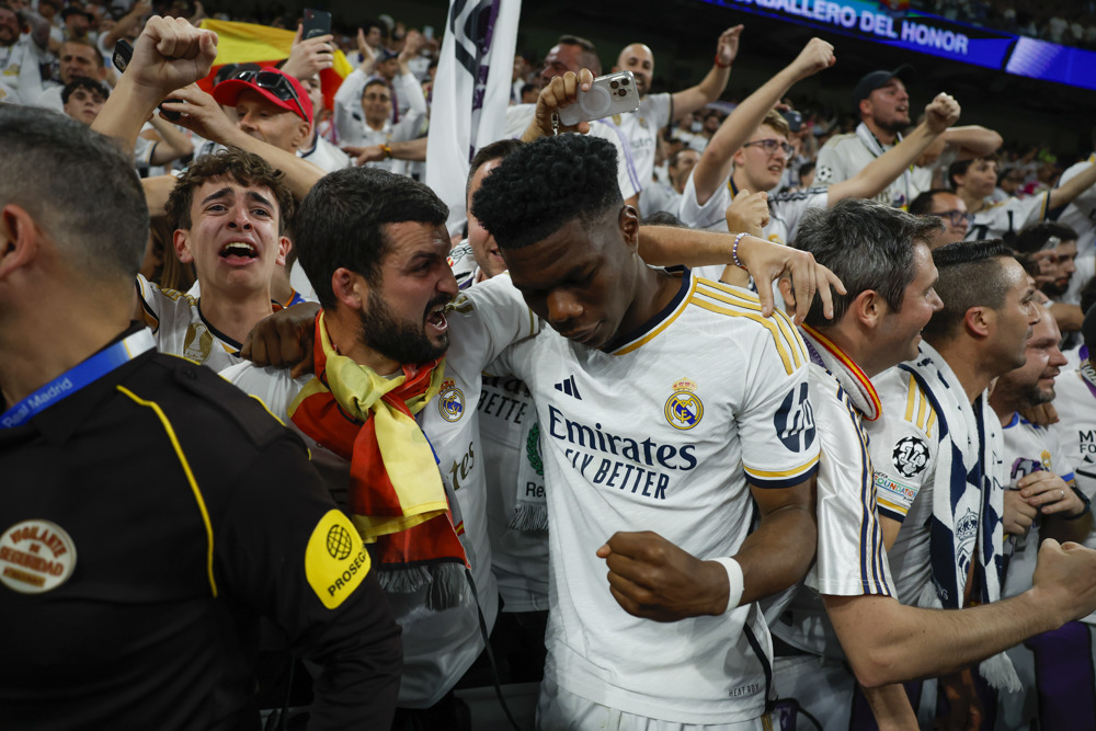 O volante francês do Real Madrid, Aurelien Tchouameni, festeja com os torcedores brancos a vitória da sua equipa no final do jogo correspondente à segunda mão das meias-finais da Liga dos Campeões