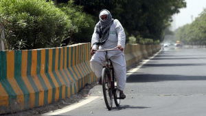 Um viajante anda de bicicleta enquanto cobre a cabeça com uma toalha num dia quente em Nova Deli, Índia, 29 de maio de 2024. O Departamento Meteorológico da Índia (IMD) emitiu um alerta vermelho de calor para Delhi, Rajastão, Haryana, Punjab e Madhya Pradesh em 29 de maio. Uma temperatura recorde de mais de 50 graus Celsius foi registrada em alguns subúrbios de Delhi, de acordo com o IMD.