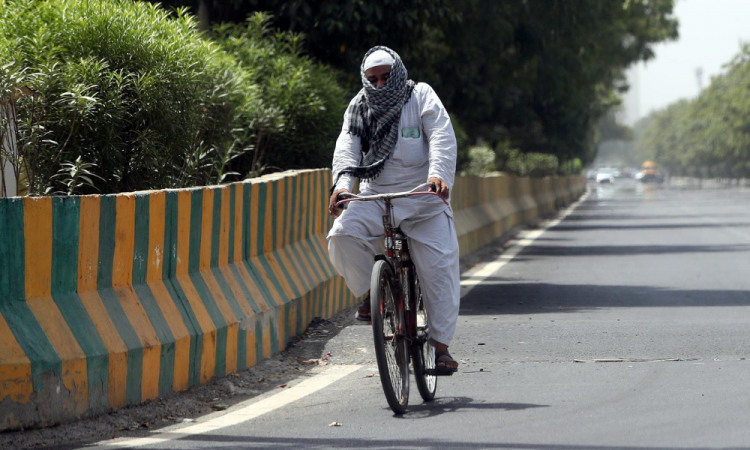 Um viajante anda de bicicleta enquanto cobre a cabeça com uma toalha num dia quente em Nova Deli, Índia, 29 de maio de 2024. O Departamento Meteorológico da Índia (IMD) emitiu um alerta vermelho de calor para Delhi, Rajastão, Haryana, Punjab e Madhya Pradesh em 29 de maio. Uma temperatura recorde de mais de 50 graus Celsius foi registrada em alguns subúrbios de Delhi, de acordo com o IMD.