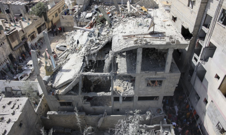 Pessoas inspecionam os danos nos escombros de um edifício que foi danificado durante o bombardeio israelense no bairro de Al-Daraj, na cidade de Gaza, em 21 de maio de 2024, em meio ao conflito em curso entre Israel e o grupo militante palestino Hamas.