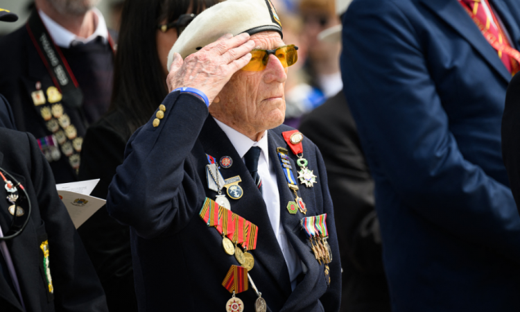 O veterano britânico da Segunda Guerra Mundial, Alec Penstone, saúda durante um desfile de veteranos do Reino Unido em Arromanches-les-Bains em 6 de junho de 2024, como parte das comemorações do 