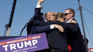 O candidato presidencial republicano, ex-presidente Donald Trump, levanta o punho enquanto é levado para fora do palco durante um comício