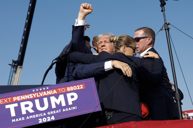 O candidato presidencial republicano, ex-presidente Donald Trump, levanta o punho enquanto é levado para fora do palco durante um comício