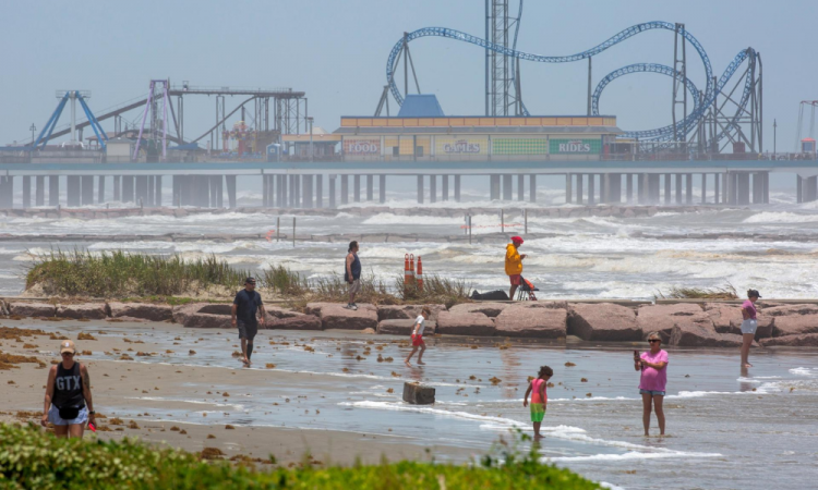 As pessoas estão sob as ondas altas antes da chegada da tempestade tropical Beryl em Matagorda, Texas, em 7 de julho de 2024. A previsão é que a tempestade se transforme em um furacão durante a noite e traga ventos fortes e chuvas fortes para a costa do Texas.