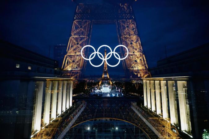 Uma foto com dupla exposição na câmera mostra a Torre Eiffel, decorada com os anéis olímpicos iluminados em Paris