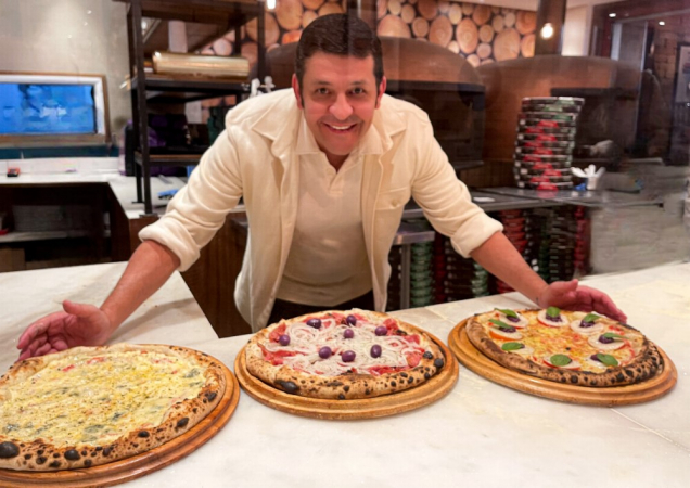 Pizzaiolo com três pizzas na mesa