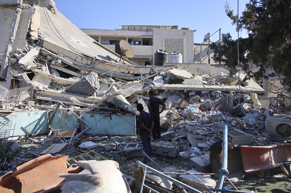 Pessoas inspecionam os danos após um bombardeio israelense na escola Al-Nassr