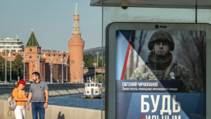 Moscou (Federação Russa), 19/08/2024.- Pessoas passam por um ponto de ônibus com um cartaz publicitário pedindo o alistamento militar, em frente ao Kremlin em Moscou, Rússia, 19 de agosto de 2024. De acordo com o vice-presidente do Conselho de Segurança da Rússia e líder do partido governante Rússia Unida, Dmitry Medvedev, desde o início de 2024, quase 200.000 pessoas assinaram contratos para o serviço militar no exército russo. (Rússia, Ucrânia, Moscou)