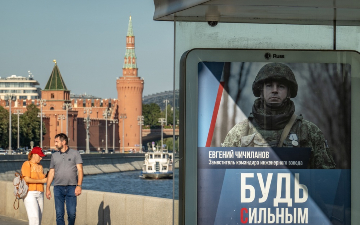 Moscou (Federação Russa), 19/08/2024.- Pessoas passam por um ponto de ônibus com um cartaz publicitário pedindo o alistamento militar, em frente ao Kremlin em Moscou, Rússia, 19 de agosto de 2024. De acordo com o vice-presidente do Conselho de Segurança da Rússia e líder do partido governante Rússia Unida, Dmitry Medvedev, desde o início de 2024, quase 200.000 pessoas assinaram contratos para o serviço militar no exército russo. (Rússia, Ucrânia, Moscou)