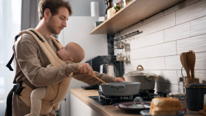 Pai cozinhando enquanto segura o bebê plano médio