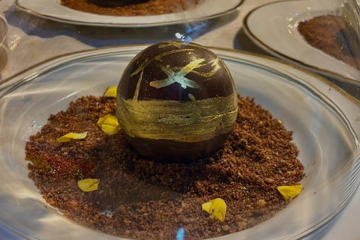 Esfera de chocolate com entremet de coco e manga e calda de chocolate 