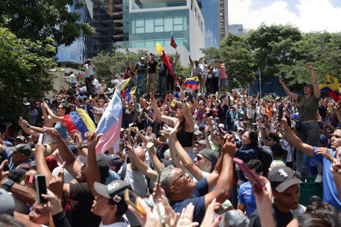 essoas observam a líder oposicionista da Venezuela, María Corina Machado, participando de uma manifestação em protesto contra os resultados oficiais das eleições presidenciais — que dão a vitória ao presidente Nicolás Maduro —, neste sábado em Caracas (Venezuela). Em cima de um caminhão, Machado chegou à manifestação em uma área do leste de Caracas, acompanhada pelos opositores Delsa Solórzano, Juan Pablo Guanipa, María Beatriz Martínez, Biagio Pilieri e Williams Dávila, todos membros de partidos que formam a maior coalizão oposicionista, Plataforma Unitaria Democrática (PUD). Até o momento, não foi confirmada a presença do candidato da coalizão, Edmundo González Urrutia.