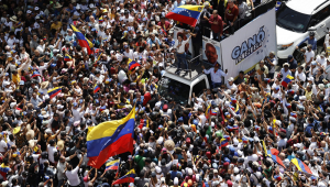 A líder da oposição venezuelana María Corina Machado (c) agita a bandeira da Venezuela diante de seguidores