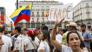 Uma mulher segura um cartaz na manifestação convocada pela oposição venezuelana um dia após as eleições no país, nesta segunda-feira em Madrid